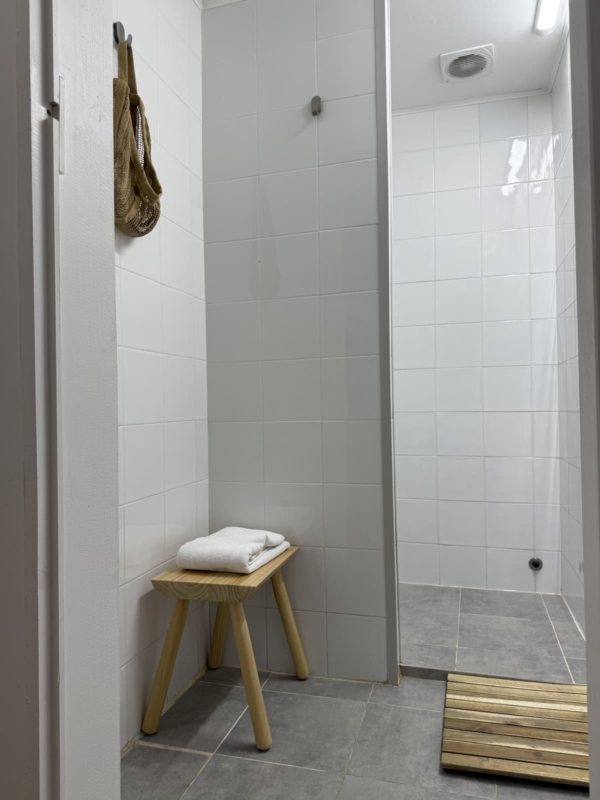 Duche do balneário do BODYFIT com banco em madeira e toalha dobrada.